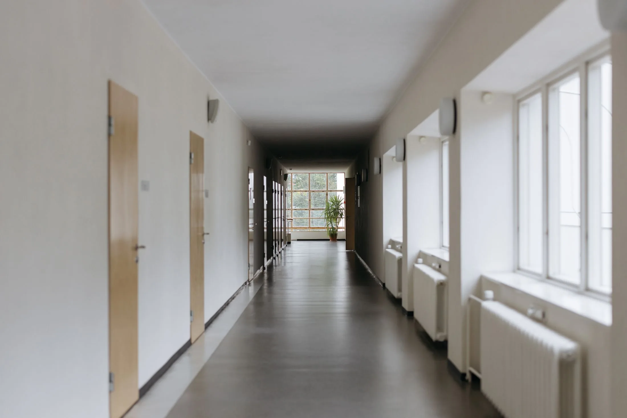 Heller Flur einer Einrichtung, an dessen Ende Tageslicht durch ein Fenster fällt.